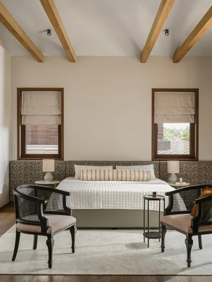 The primary bedroom is minimal yet impressive, with a calming presence. We used a low, patterned headboard that spans the width of the wall and added floating wooden rafters to the vaulted ceiling for architectural interest.
