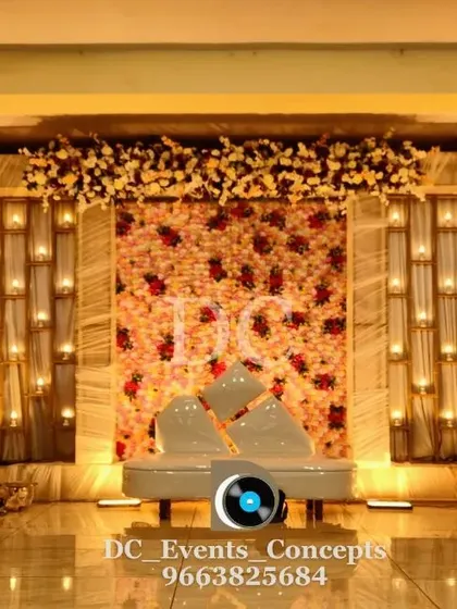 A sophisticated Sangeet stage with a floral wall and candle-lit panels. The modern sofa and warm lighting create an intimate and stylish ambiance for an evening of music and dance.