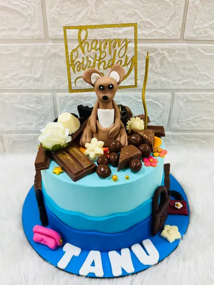 A unique and adorable kangaroo-themed birthday cake. This design features a cute fondant kangaroo surrounded by chocolates and other sweet treats.