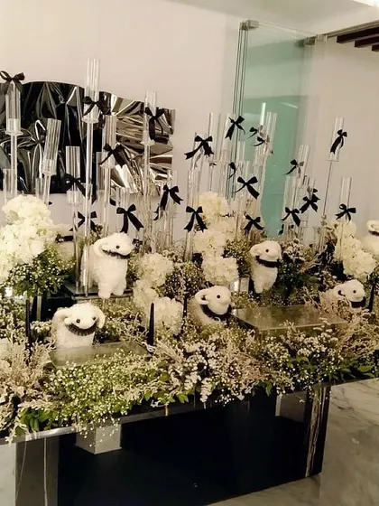 A modern and whimsical tablescape with white floral arrangements and smiley-faced props, all tied together with black bows.