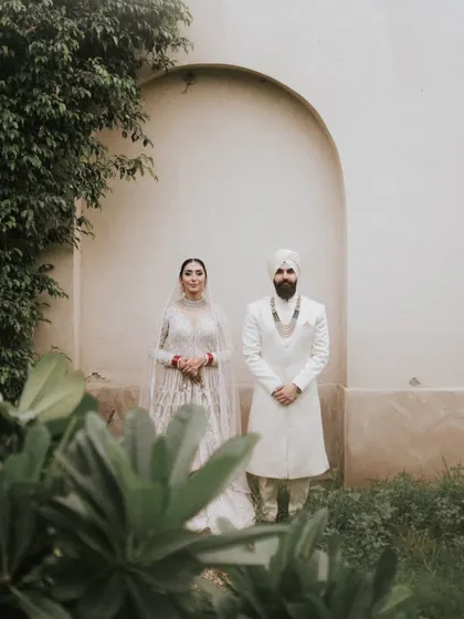 A classic portrait of the Sikh bride and groom. Their coordinated white outfits exude grace and elegance, reflecting the sophisticated decor of their wedding.