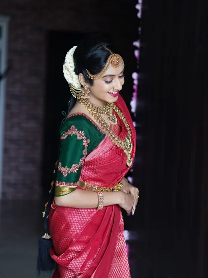 A candid shot of a bride in a classic red and green Kanjivaram saree, perfectly styled with my layered antique temple jewellery set.