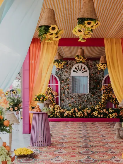 A detailed shot of a Haldi decor setup. The hanging floral baskets, patterned carpets, and flower-adorned walls created a beautiful and immersive environment.