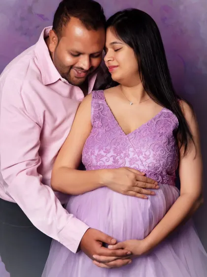 A close-up shot capturing the tender connection between the expecting couple. Dressed in a lovely lavender gown, the mom-to-be shares a quiet moment with her partner.