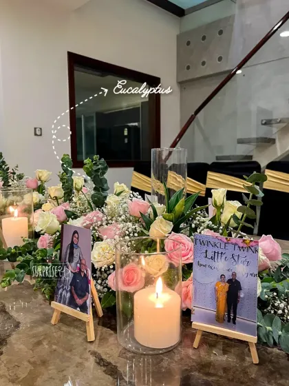 A close-up of the 50th-anniversary tablescape. We used mini photo easels displaying the couple's memories alongside pillar candles and delicate arrangements of roses and eucalyptus.