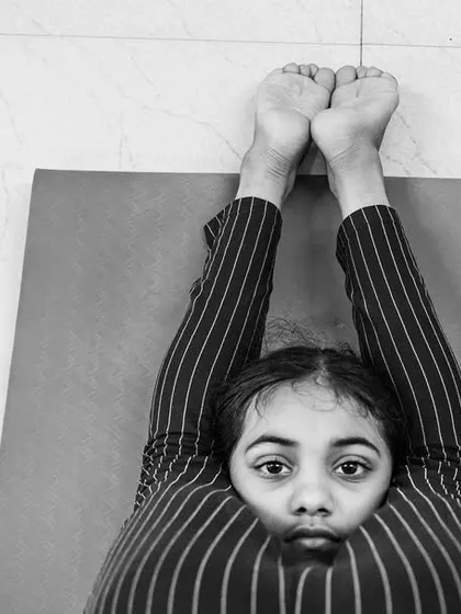 Yoga is a journey of connecting with the self. This powerful image of a young girl in a deep forward bend shows the focus and introspection that can be found even at a young age.