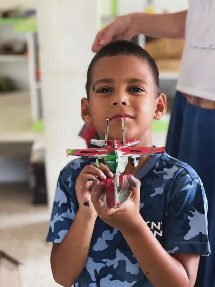 A young artist proudly displays the F18 fighter plane model he painted himself.
