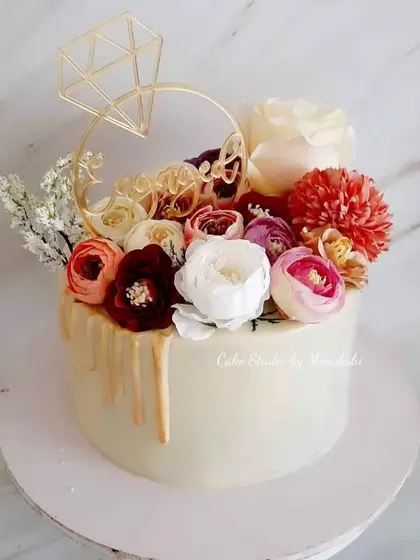 Perfect for a small and intimate engagement party. This no-fondant cake has a golden drip effect and is crowned with a beautiful bouquet of flowers and a diamond ring topper.