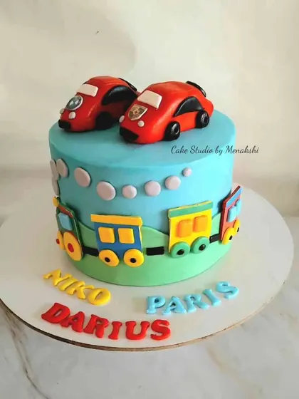 A fun transport themed cake for triplets. This design features cars and a train, with each of the children's names written in colourful letters.