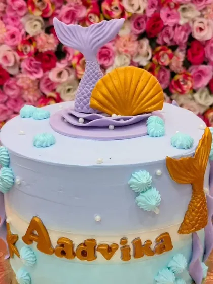 A close-up of the pastel mermaid cake, focusing on the delicate fondant shell and mermaid tail topper.