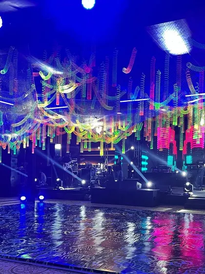 The dance floor and stage setup under our custom neon slinky installation. The reflective flooring mirrored the vibrant colors from above, amplifying the energy of the event space.