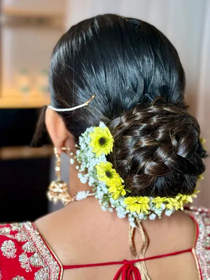 A traditional bridal bun decorated with vibrant yellow flowers, perfect for a Haldi or wedding ceremony.