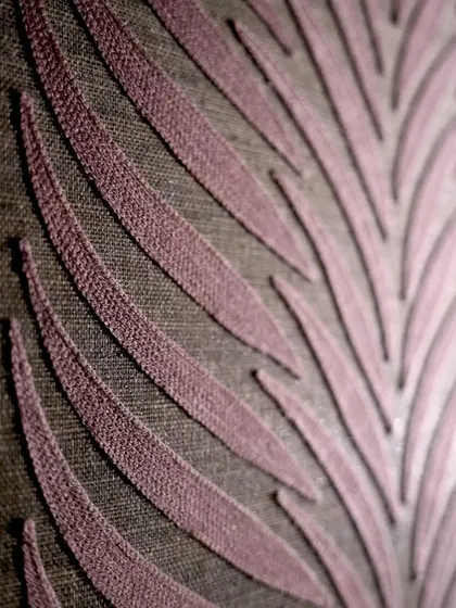 The 'Ornementa' wallcovering by Casamance uses a warm color harmony inspired by palaces. This detailed view shows the elegant plum shade and refined texture, capturing an atmosphere where time seems to stand still.
