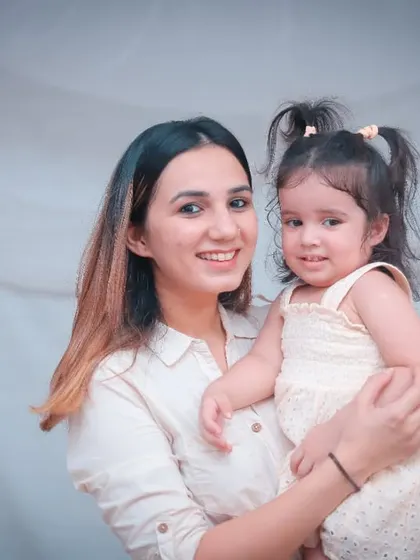 A sweet portrait of a mother holding her two-year-old daughter, both looking at the camera.