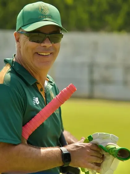 A bright and sunny day is best spent playing cricket with teammates. A coach smiles, ready for another great session.
