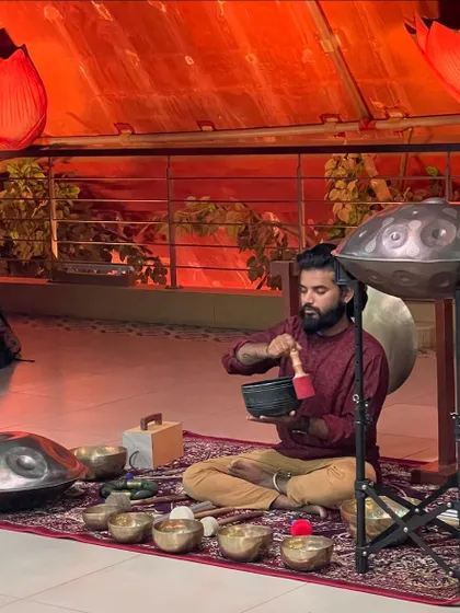 Playing the singing bowl during a session in Bangalore. The lotus-themed decor in the background adds to the spiritual and calming ambiance of the sound journey.