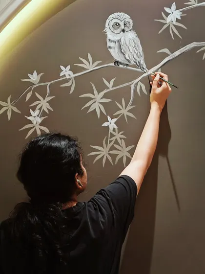 A close-up of me painting a wise owl inside a wall arch. This was a favorite element from a larger kid's room project.