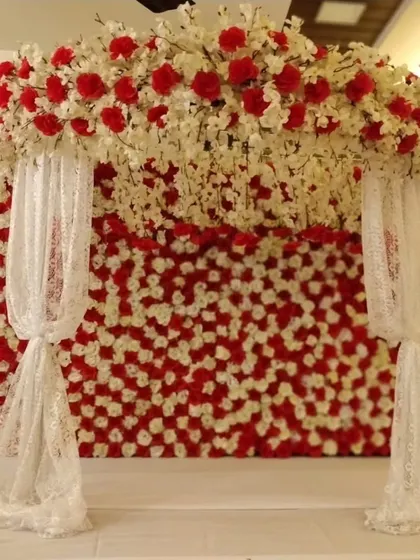 This Navratri or Ganpati decor combines a wall of red and white flowers with delicate lace drapes for a look that is both bold and soft.