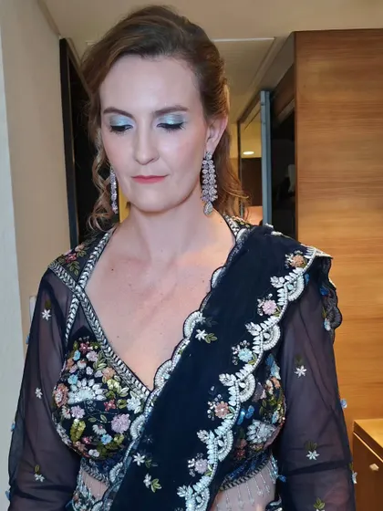 A glamorous look for this wedding guest. We went with a shimmery blue eyeshadow to match her lehenga and a romantic, curly half-updo.