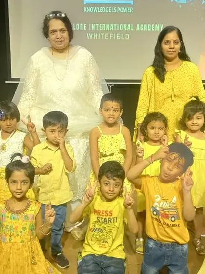 A group of happy campers in yellow poses with their teachers after their performance.