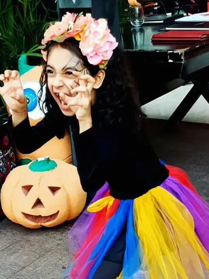Are your costumes ready? This little guest shows off her fierce pose next to a jack-o'-lantern, getting into the playful spirit of our Halloween celebration.