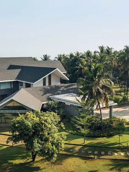 A view of the Mangalore home from the driveway, showing how the structure is integrated with the lush, tropical landscape. The design creates a private oasis that feels both luxurious and connected to its surroundings.