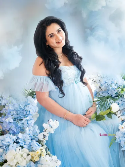 A happy, smiling portrait of the mom-to-be, surrounded by beautiful blue flowers.