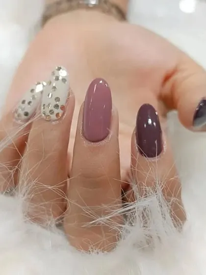 A mix-and-match set in muted tones of mauve and purple, with a fun polka-dot glitter accent nail.