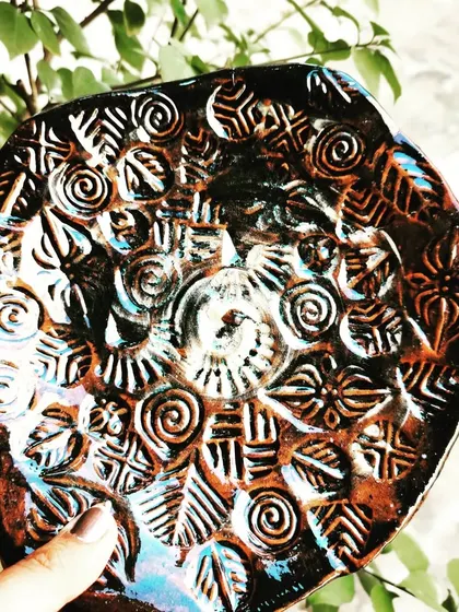 The intricate stamped patterns on this platter are highlighted by the dark, rustic finish from the firing process, resulting in a piece with incredible depth and texture.