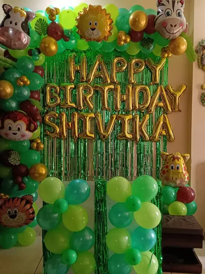 A classic jungle safari theme, perfect for a home party. I used a green tinsel backdrop and a green balloon frame, decorated with various animal head foil balloons like a monkey, lion, and zebra.
