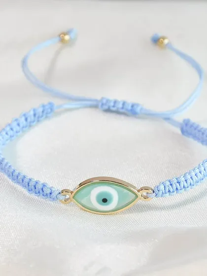 A close-up of one of my braided evil eye rakhis in a beautiful pastel blue. It's a modern take on a traditional symbol.