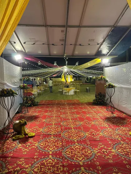 The entrance to the outdoor Haldi event, with a grand red carpet leading towards the beautifully lit canopy. This view builds anticipation for the celebration ahead.