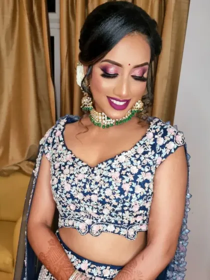 A modern reception look with a floral embroidered lehenga. The makeup is fun and vibrant, with a pop of purple on the eyes and lips.