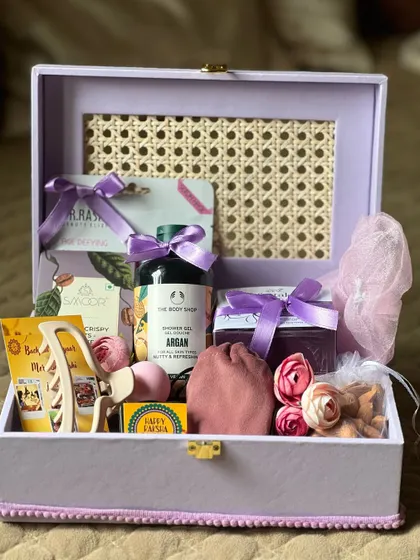 This elegant Rakhi hamper includes gourmet chocolates, a face mask, a hair clip, and other accessories.