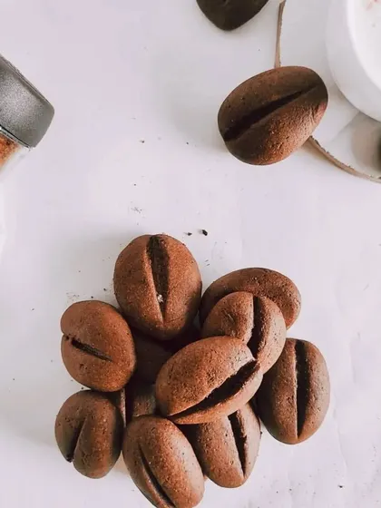 A flatlay of coffee bean-shaped cookies on a clean white surface. This creative shot is perfect for a coffee shop or a baker who wants to showcase their unique creations.