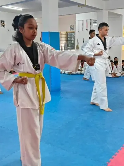 A young girl in the foreground leads her line in practicing a punch.