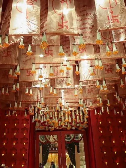 A view of the entrance ceiling, adorned with Sanskrit-scripted drapes and hanging floral tassels, creating a sacred and traditional feel.