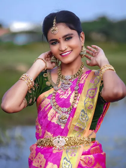 A full portrait of the model, showing the complete AD set against a pink and green saree.
