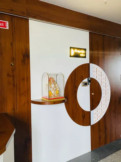 A unique entrance design where the main door and wall panel form a single circular motif. A small niche with a Ganesha idol adds a sacred touch.