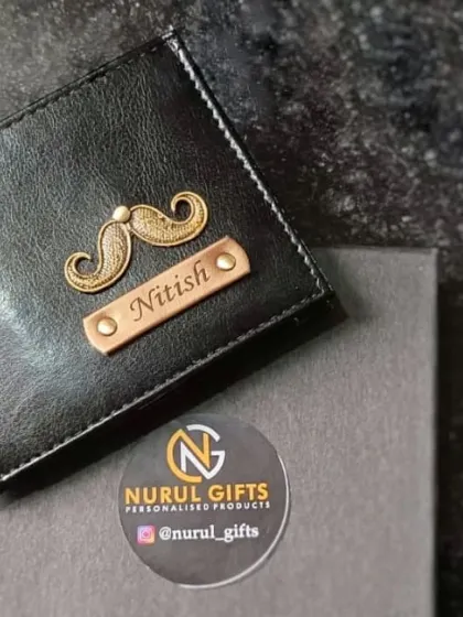 A classic black personalized wallet with a mustache charm and the name 'Nitish', presented in its elegant gift box.
