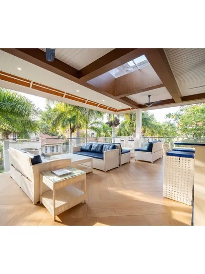 This bespoke terrace sit-out is the epitome of outdoor luxury. It features a sophisticated bar unit, comfortable wicker seating with navy cushions, and a high ceiling with skylights, seamlessly blending style and functionality.