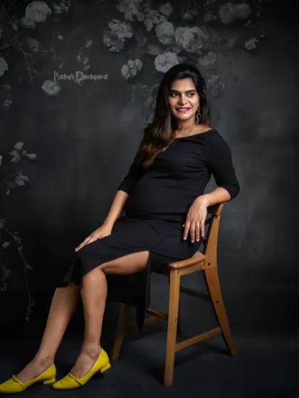 A portrait of strength and grace. This expecting mother looks absolutely radiant and confident in this classic studio shot against a dark floral background.