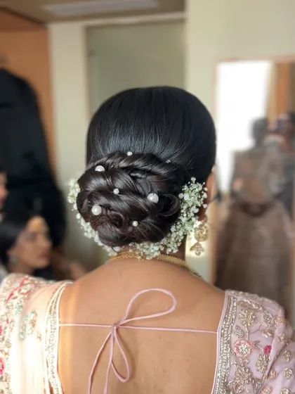A beautiful and intricate low bun, decorated with baby's breath and pearls, a very popular and romantic choice for receptions.