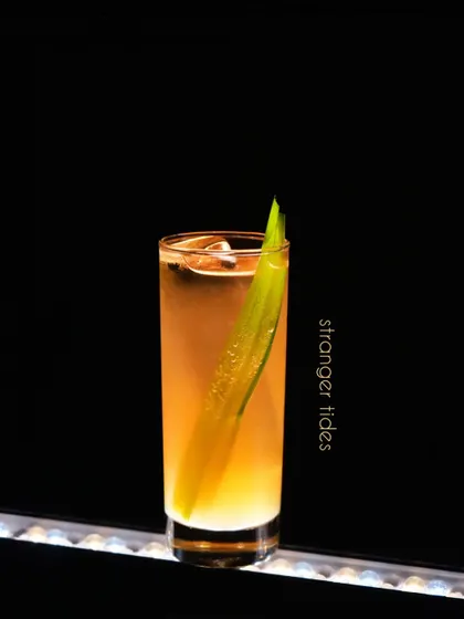 The Stranger Tides cocktail is an intriguing highball with a unique profile. The long pandan leaf garnish imparts a subtle, sweet aroma that complements the drink's layered flavors, making for a truly memorable experience.