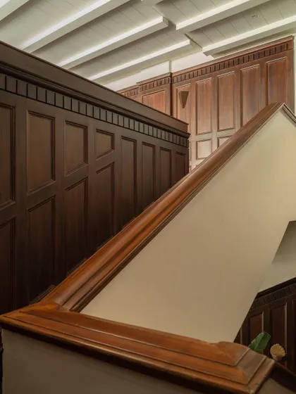 A detail of the rich mahogany-hued wood paneling and staircase at Lord Elgin, Ludhiana. This element introduces a sense of history and gravitas, its classic form in dialogue with the modern restraint of the space.