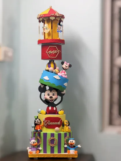 The full 5-tier Mickey Mouse topsy-turvy cake, featuring a rotating carousel on top and a gravity-defying tier held up by Mickey himself.