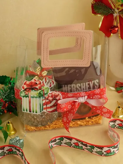 This clear bag with pink handles contains Hershey's Kisses and other treats. It's a cute and affordable Christmas gift, decorated with a festive ribbon and sticker.