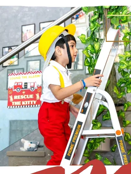 The birthday boy, dressed as a firefighter, enjoys the ladder-climbing activity.