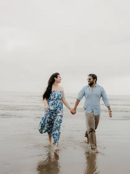 Walking hand-in-hand through the shallow waves, sharing a look of love. A simple, classic, and beautiful moment from their coastal pre-wedding shoot.