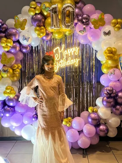 The birthday girl posing in front of her beautiful butterfly-themed backdrop.